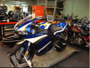 A blue and white motorcycle is on display in a garage