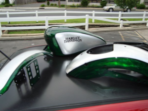 A harley davidson motorcycle sits on top of a red car