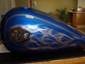 A blue harley davidson motorcycle tank with flames painted on it
