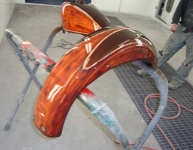 A motorcycle is being painted in a paint booth