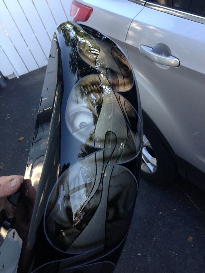 A person is holding a black object in front of a car