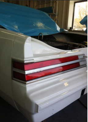 The back of a white car with the hood open