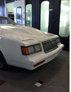 A white car is parked in a paint booth