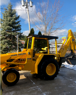A yellow john deere tractor is parked in the snow