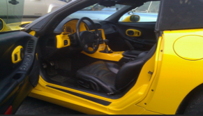 The inside of a yellow sports car with the door open