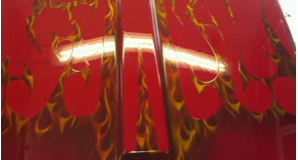A close up of a red car with flames painted on it.