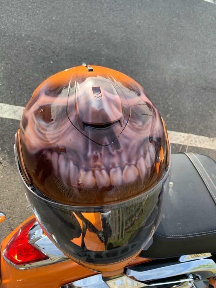 A motorcycle helmet with a skull on it is sitting on the back of a motorcycle.