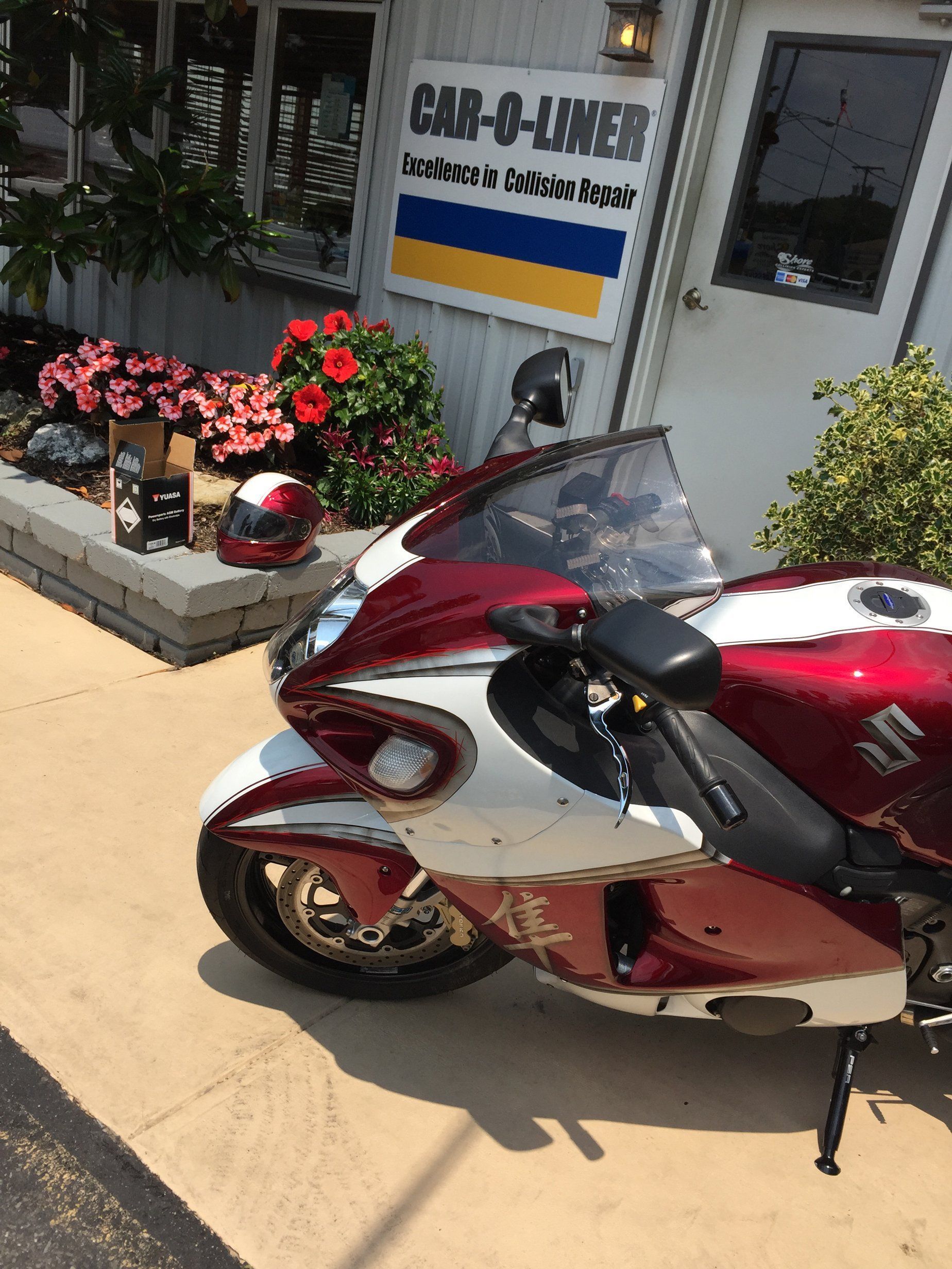 A red and white motorcycle is parked in front of a building that says cab-a-liner