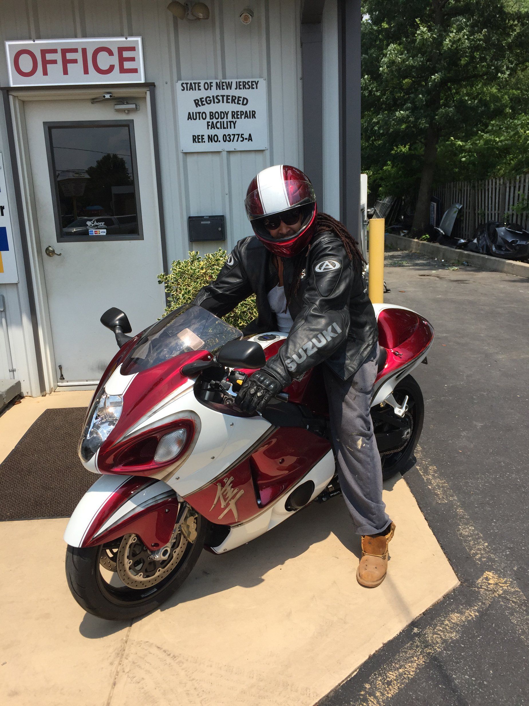 A man is riding a red and white motorcycle in front of an office