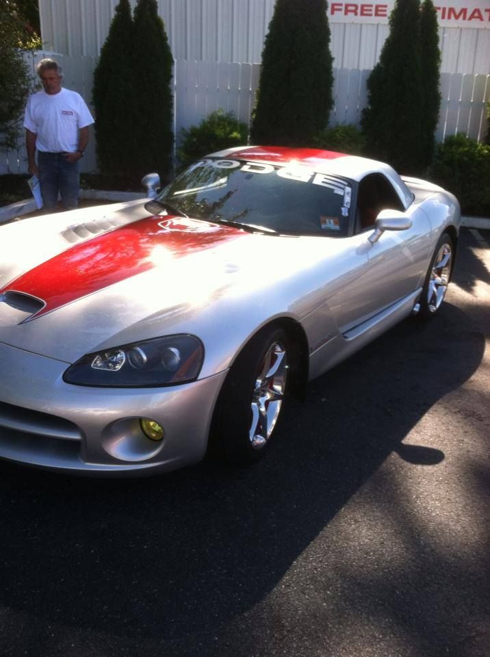A silver sports car is parked in front of a free estimate sign
