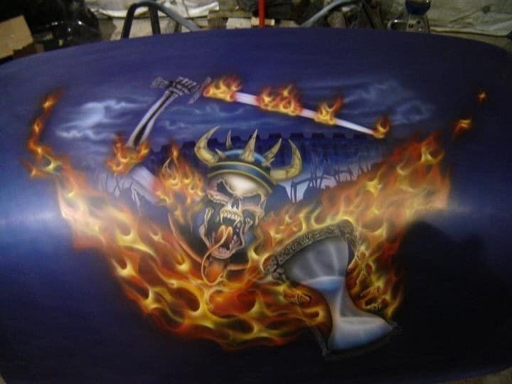 A painting of a skull with flames and a guitar