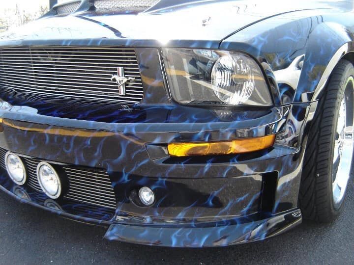 A black mustang with blue flames painted on it