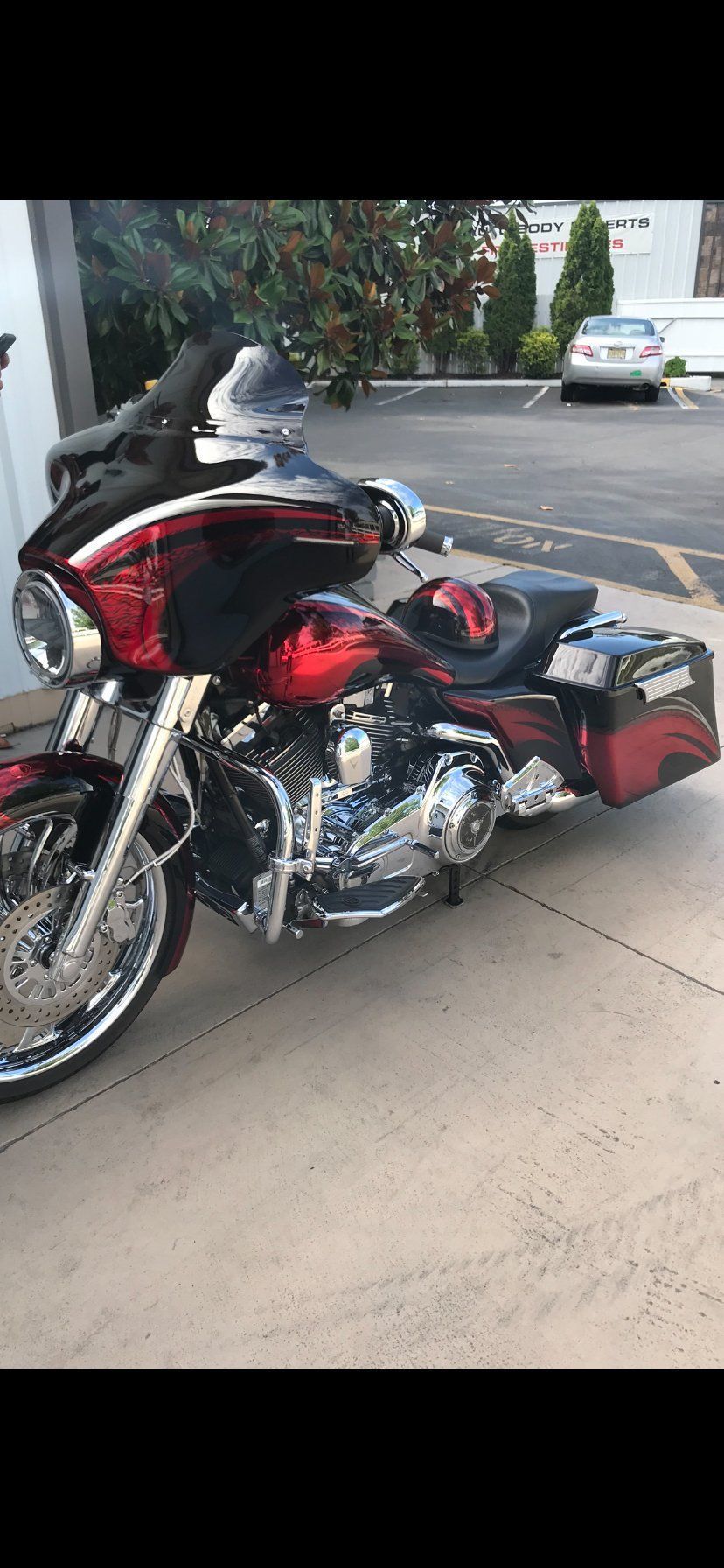 A red and black harley davidson motorcycle is parked in a parking lot.