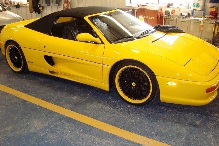 A yellow sports car with black wheels is parked in a garage