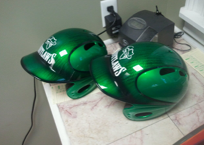 Two green baseball helmets with the word hawks on them