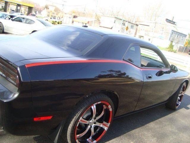 A black dodge challenger is parked in a parking lot