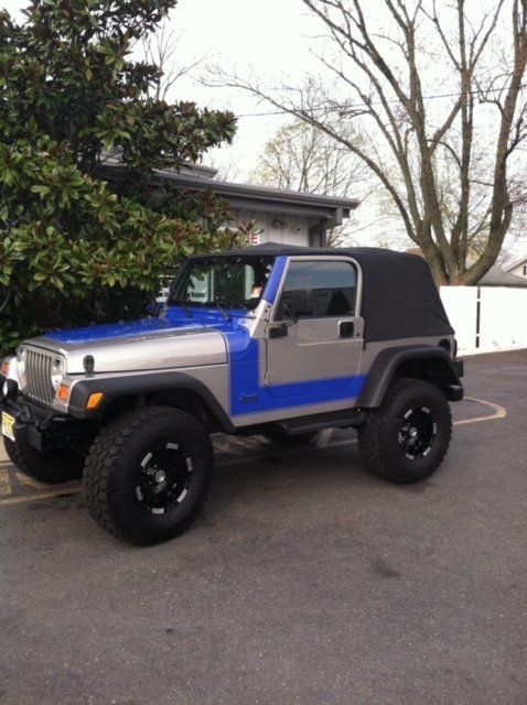A blue and silver jeep is parked in a parking lot