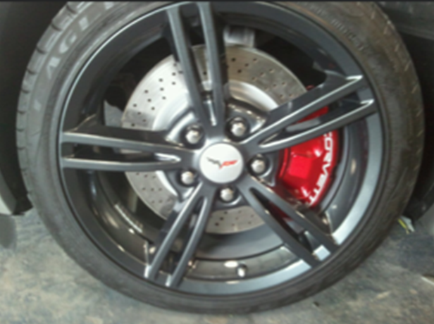 A close up of a corvette wheel with red brake calipers