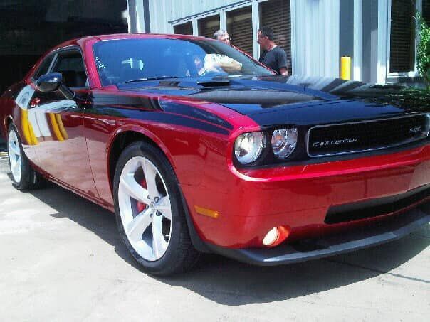 A red dodge challenger is parked in front of a building