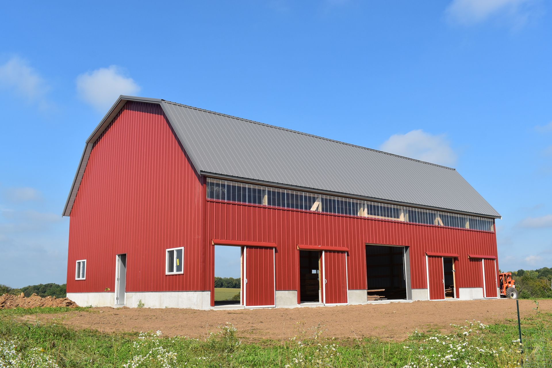 Red barn with gray roof under a clear blue sky.