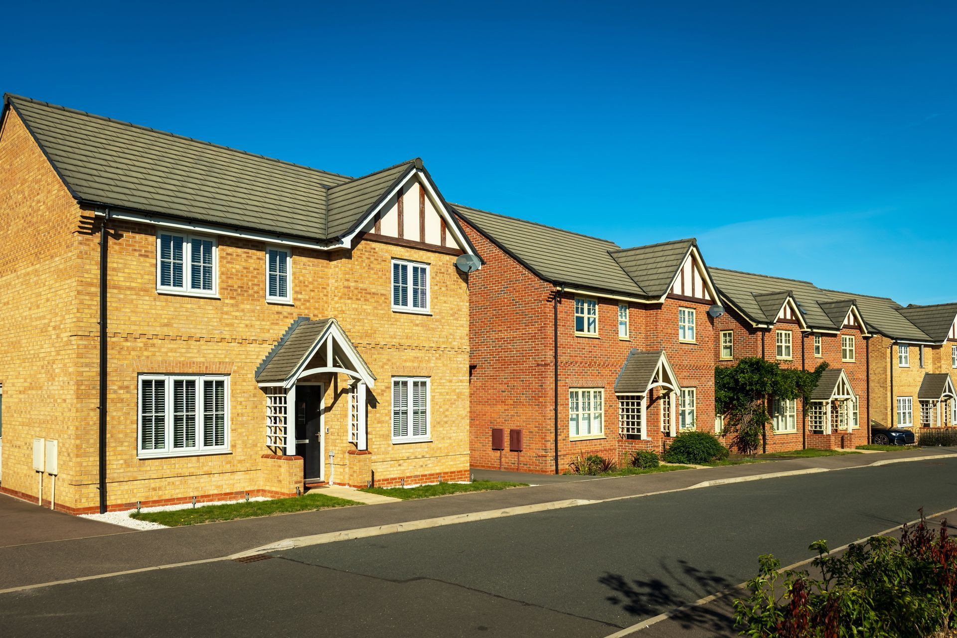 Row of brick houses with white trim, gray roofs, and a blue sky.