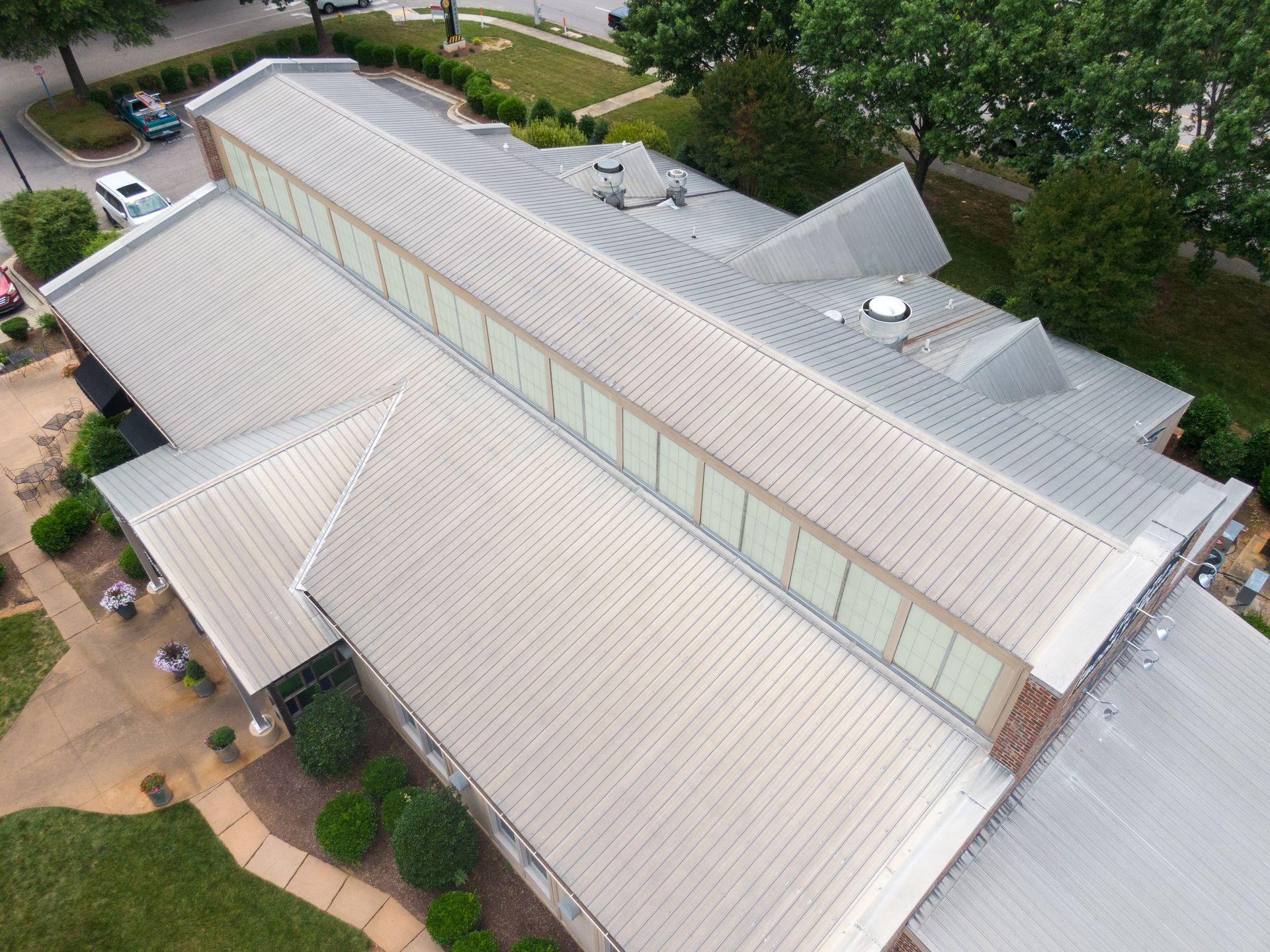 Overhead view of a building with a multi-sectioned metal roof with windows in the center.