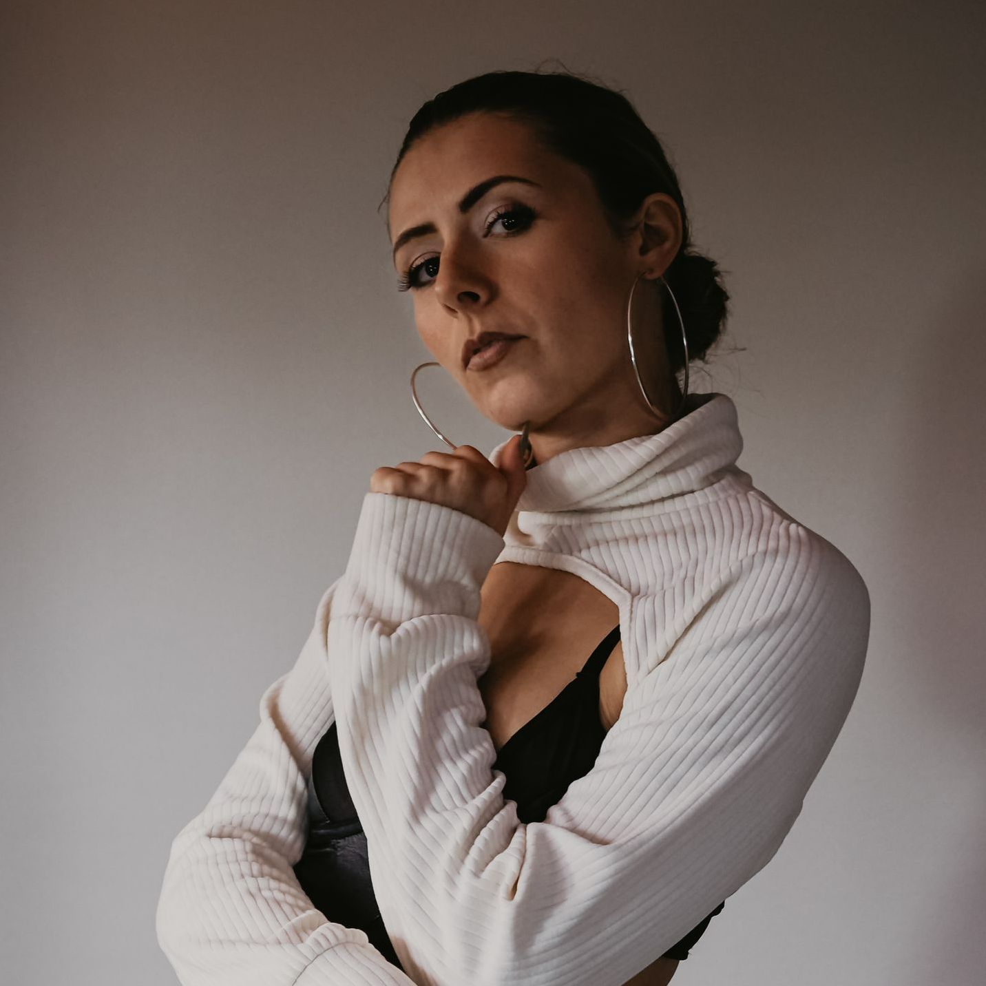 A woman wearing a white sweater and hoop earrings