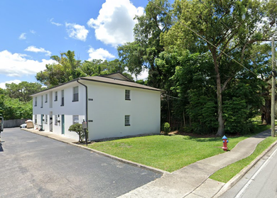 A white apartment building with a parking lot in front of it