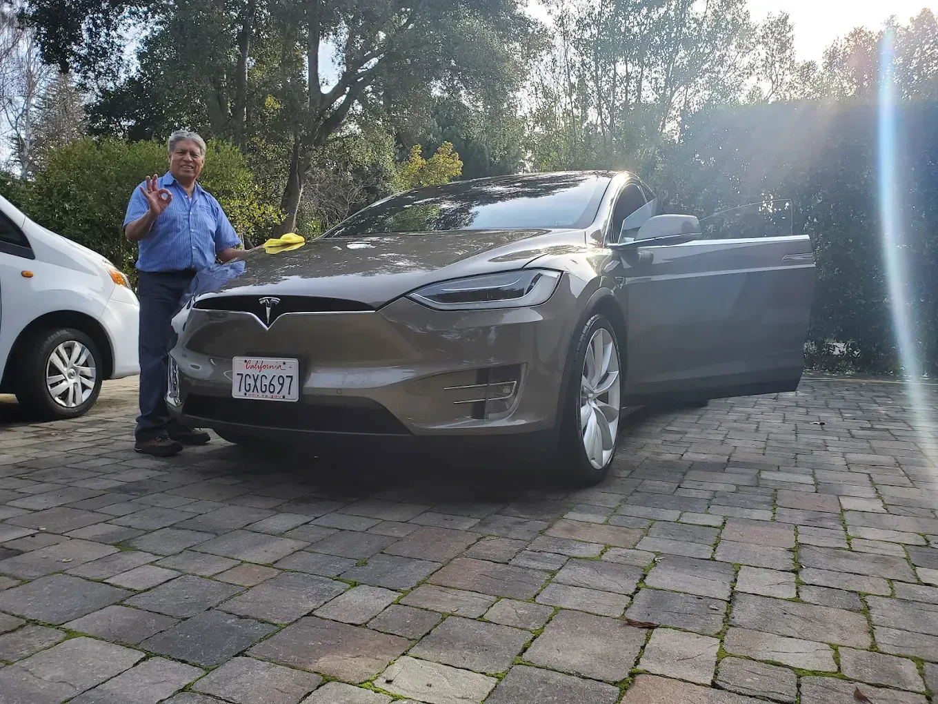Man stands next to a gray Tesla with the door open, giving an 