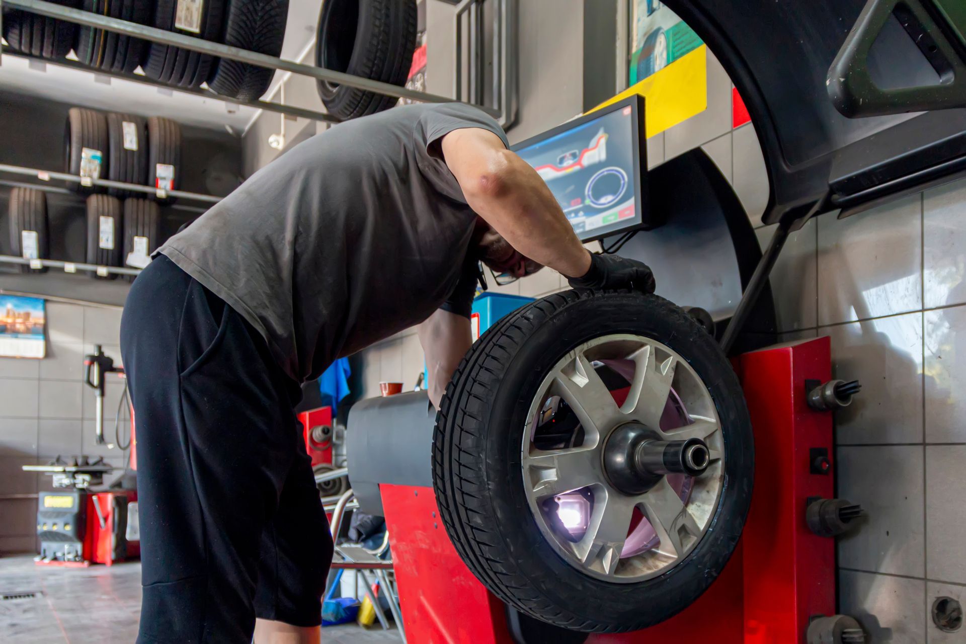 Mechanic balancing a tire on a machine in a garage.