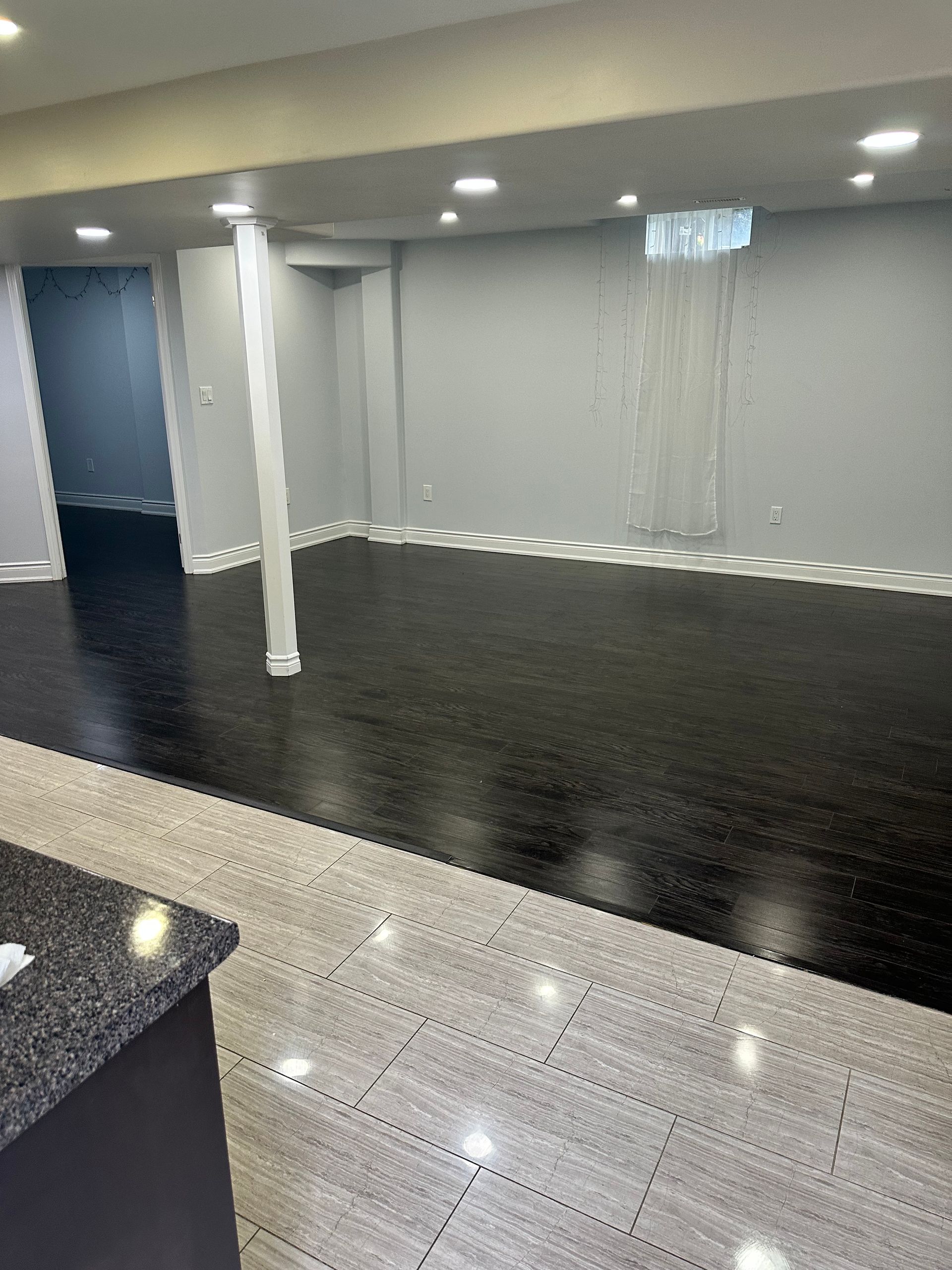 A large empty room with a black floor and gray walls.