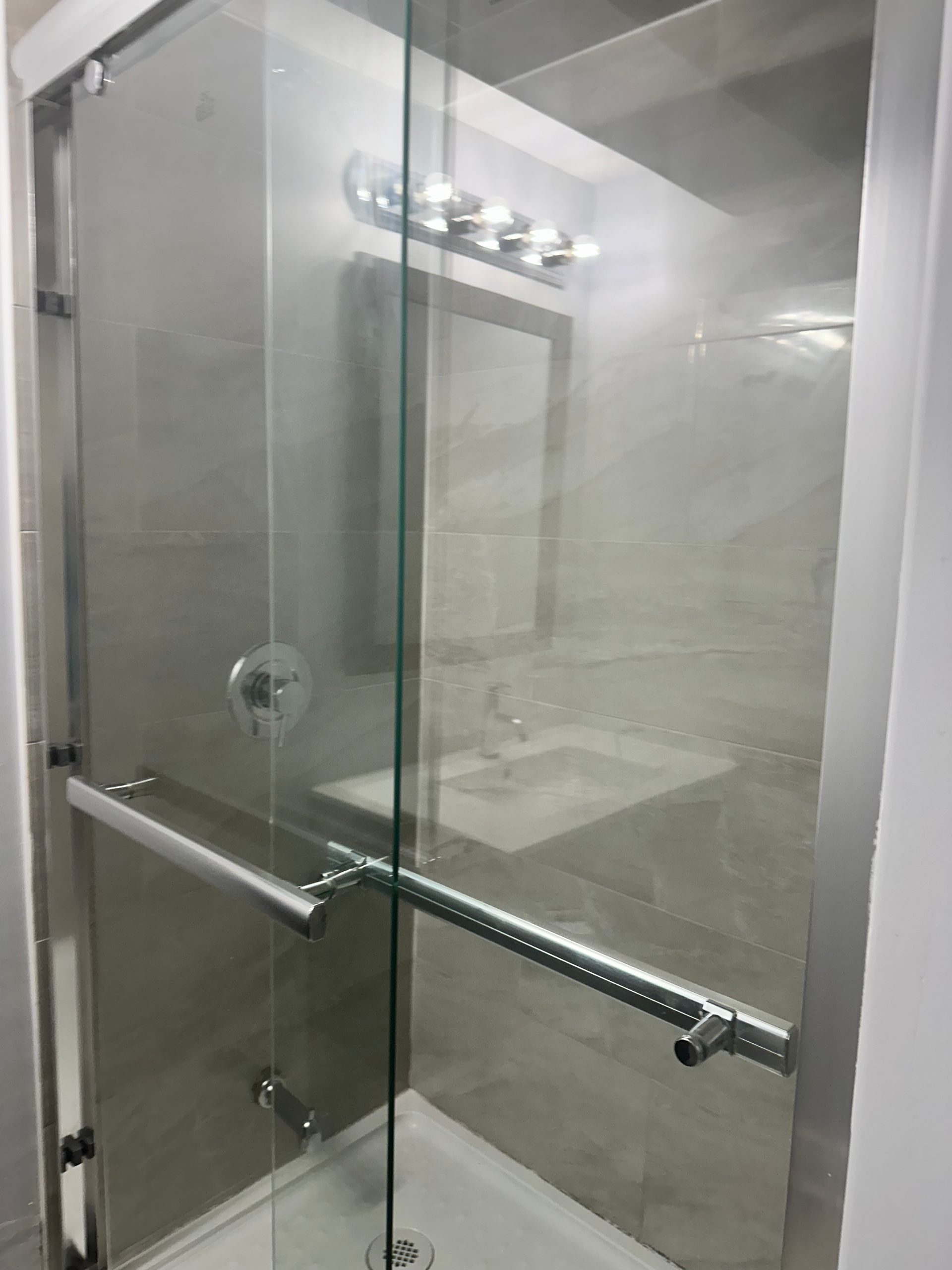 A bathroom with a glass shower door and a sink