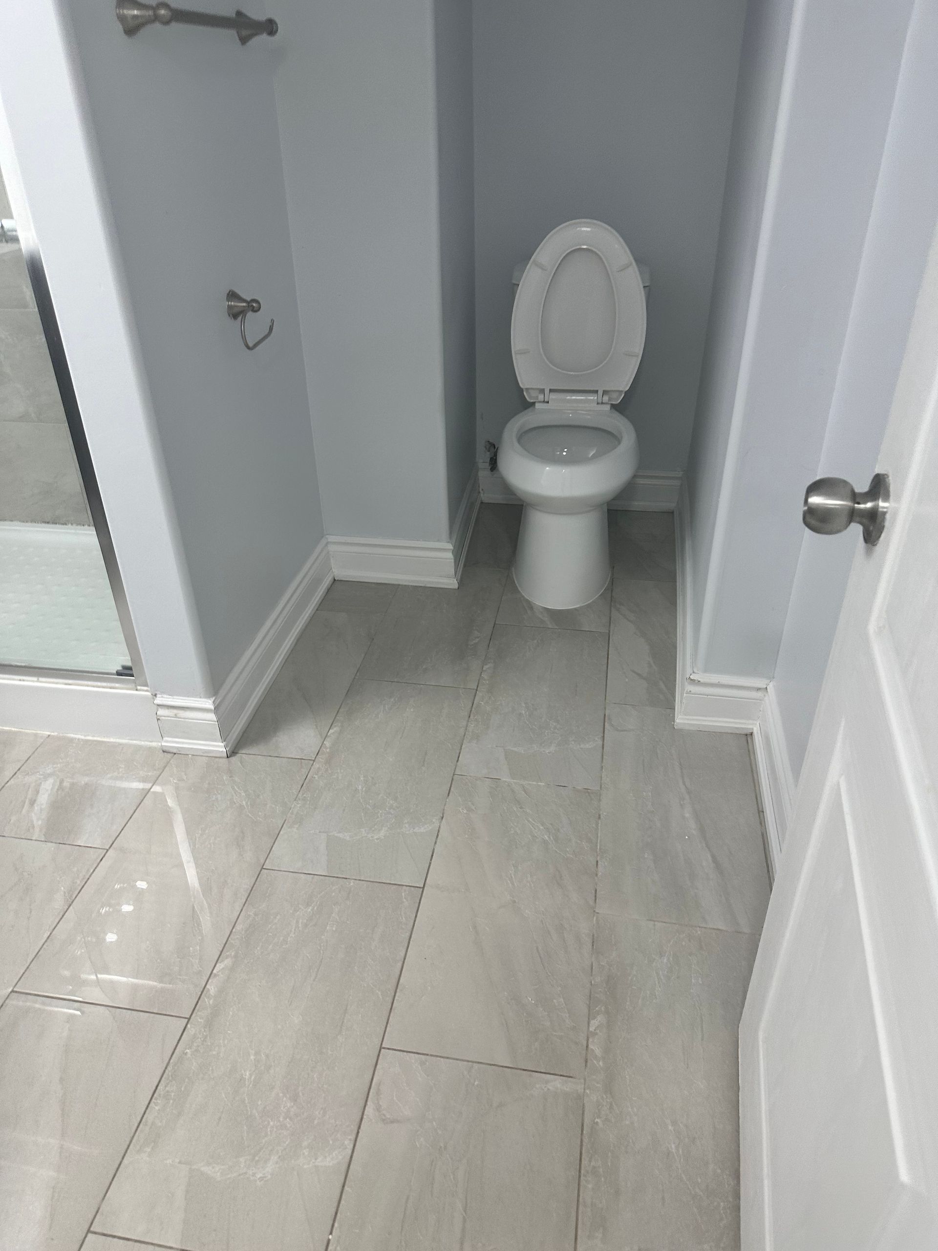 A toilet is sitting in a bathroom next to a door.