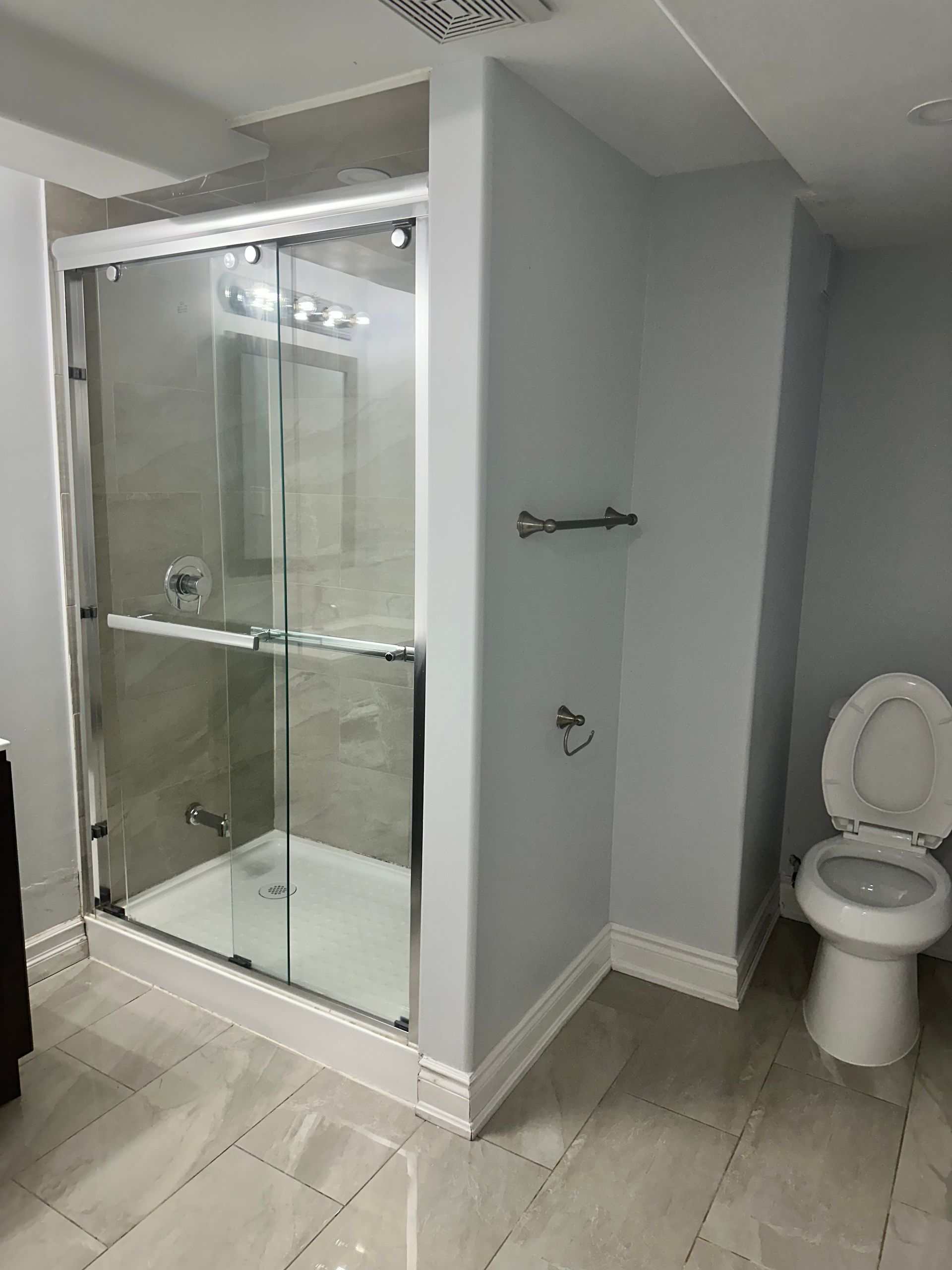 A bathroom with a toilet and a shower with sliding glass doors.