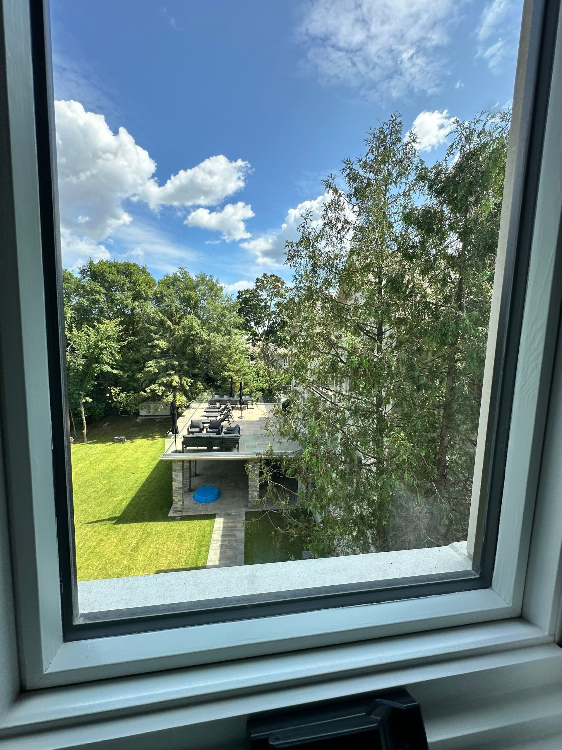 A view of a house through a window with trees in the background.