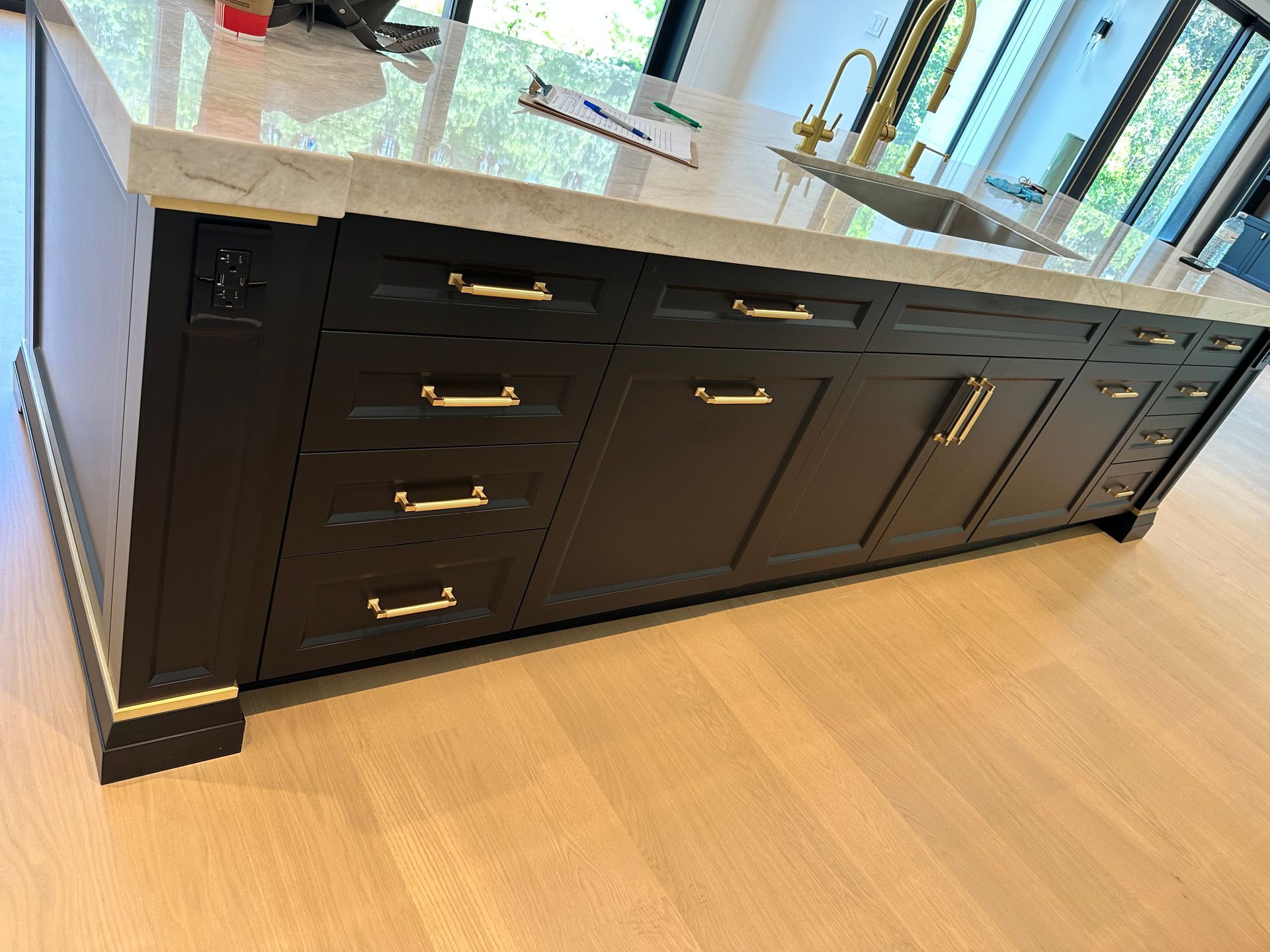 A kitchen island with black cabinets and gold handles.