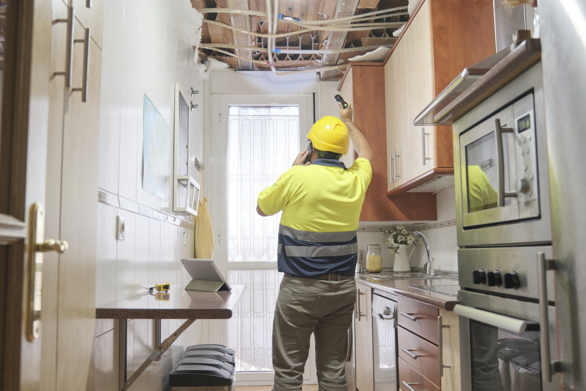 A man is standing in a kitchen looking at the ceiling.