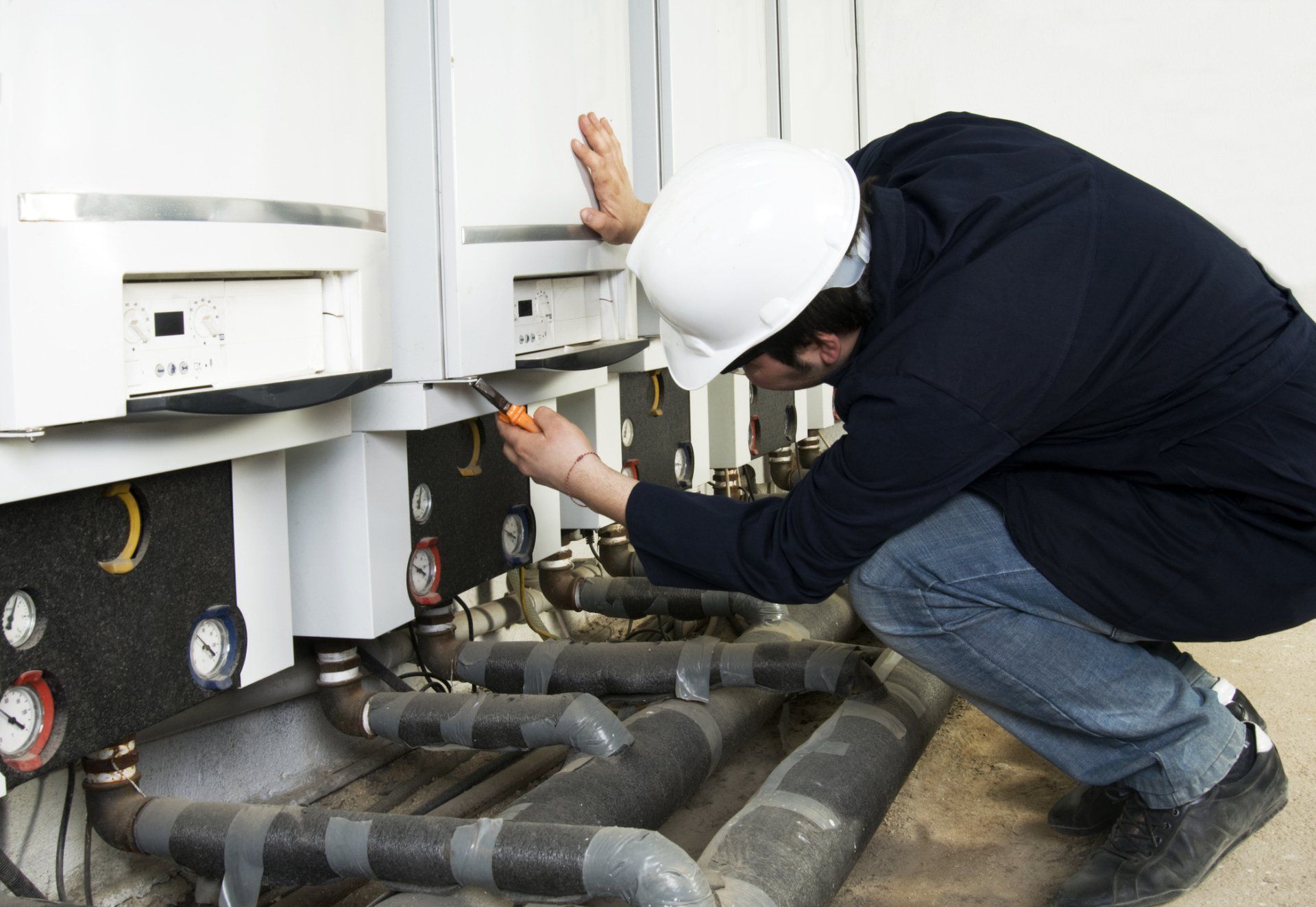 A man wearing a hard hat is working on a machine