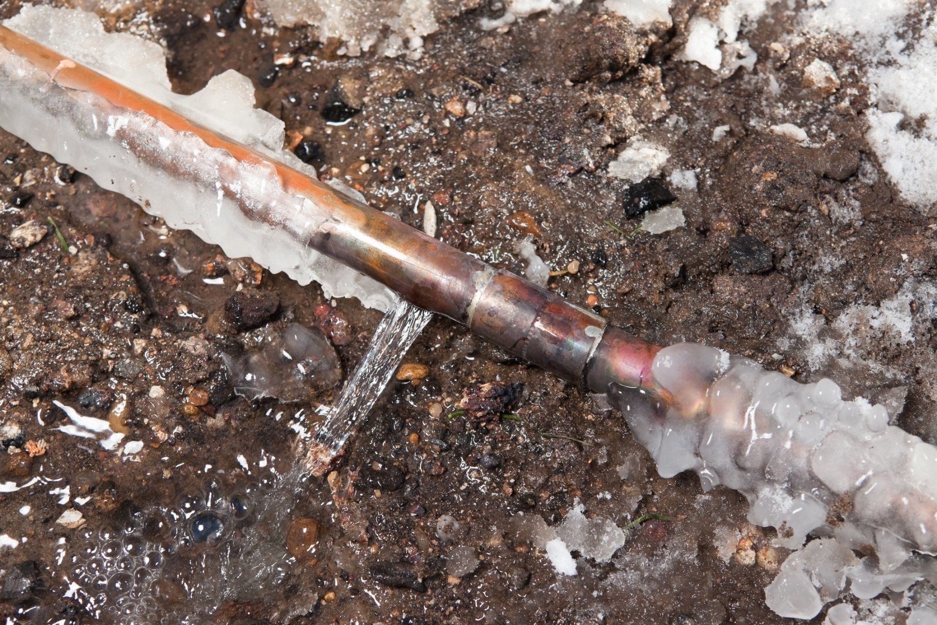 A copper pipe is covered in ice on the ground