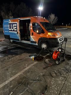 An orange and blue van is parked in a parking lot at night.