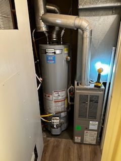 A water heater is sitting next to a furnace in a room.