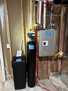 A water softener and a water heater are sitting next to each other in a basement.