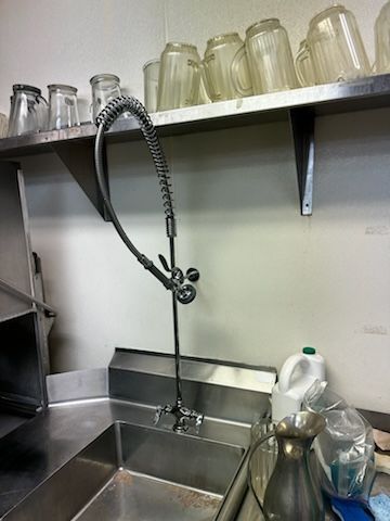 A stainless steel sink with a faucet in a kitchen.