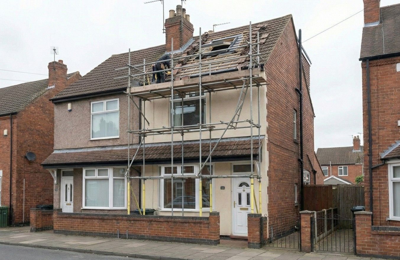 Derbyshire Specialists Group an exterior view showing a loft conversion in progress, with scaffolding erected and workers installing the Velux window into the roof of a Derby house.