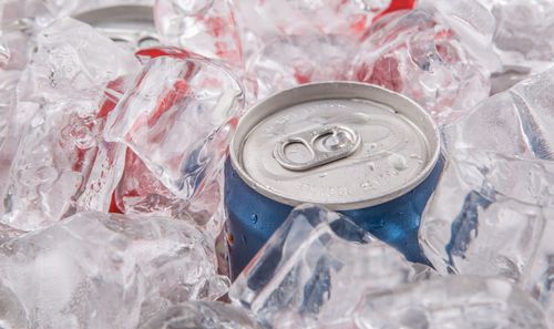 A can of soda is sitting on top of ice cubes.