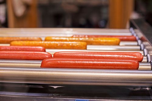 A bunch of hot dogs are cooking on a grill.