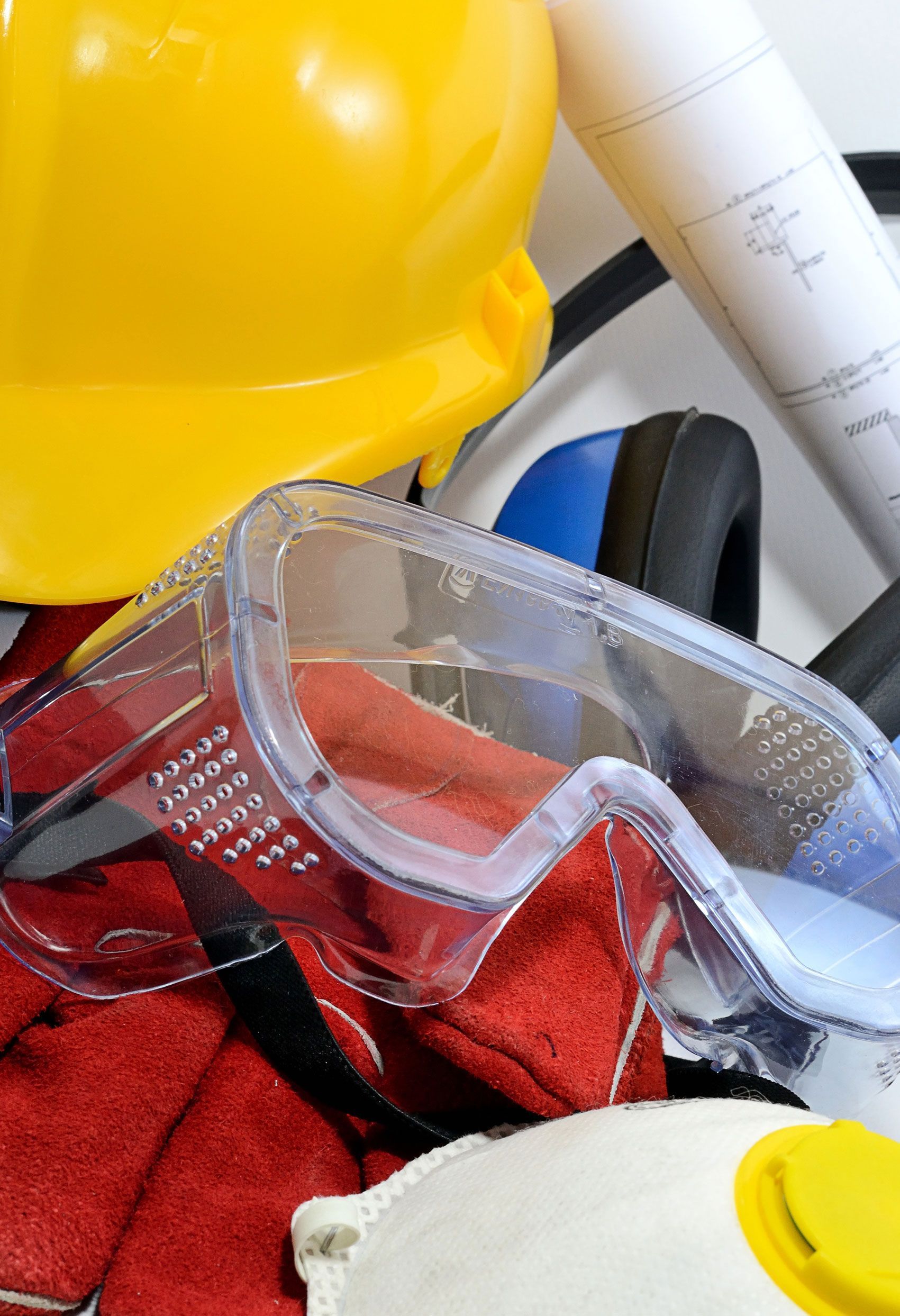 Casco amarillo, gafas de seguridad, protección para los oídos y planos, probablemente equipo de seguridad para la construcción.
