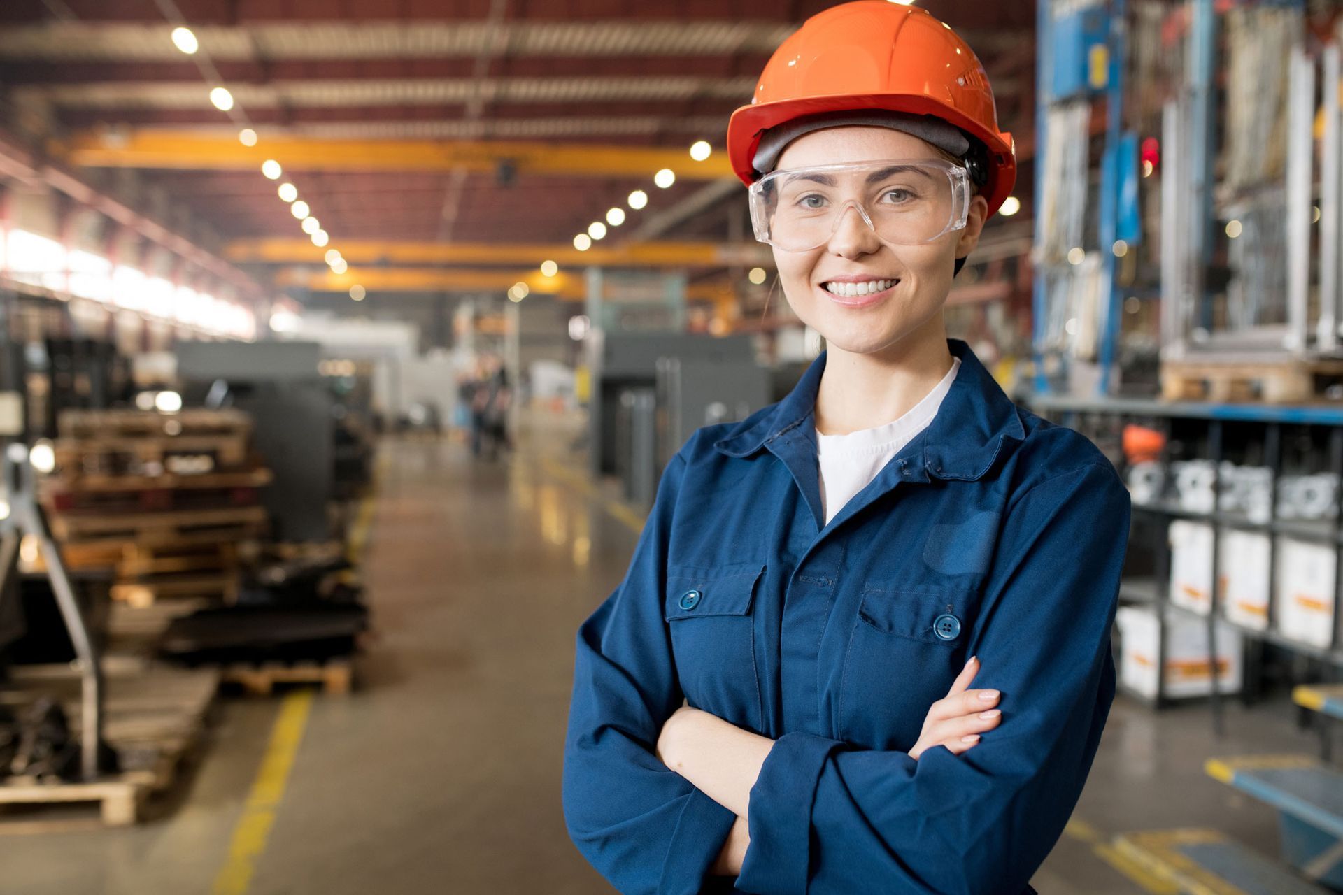 Una mujer con equipo de seguridad sonríe en un entorno industrial.