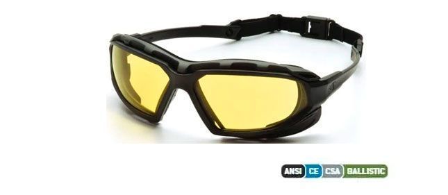 Gafas de seguridad negras con lentes amarillas. Correa negra sujeta a la montura.