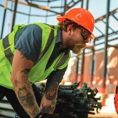 Trabajador de la construcción con equipo de seguridad inspeccionando vigas metálicas.